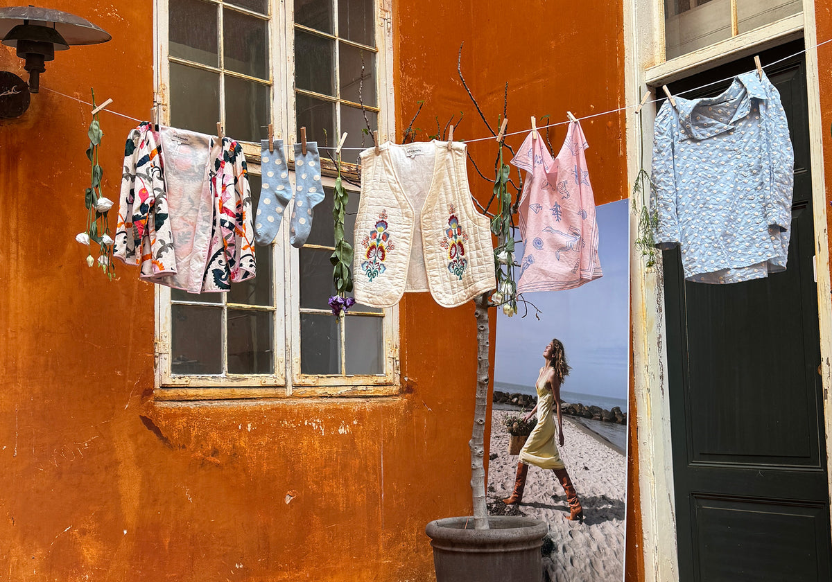 Colourful Lollys Laundry styles and accessories hanging on a clothesline in front of an orange wall in Copenhagen.